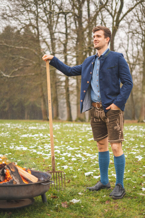 Blauer Janker kombiniert mit hellblauem Trachtenhemd, kurzer Lederhose und Trachtenkniestr&uuml;mpfen